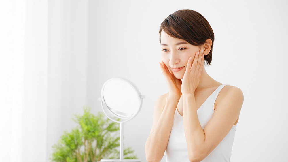 鏡の前でスキンケアする女性